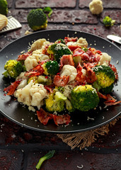 Steamed Broccoli, Cauliflower Salad with Bacon, parmesan cheese in a black plate. healthy food concept