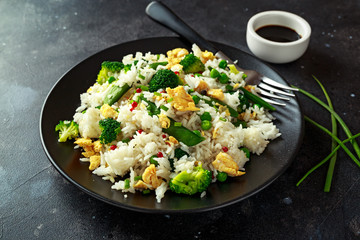 Fried rice with vegetables, broccoli, peas and eggs in a plate. healthy food