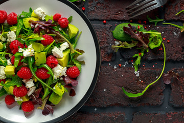 Fresh Tasty Raspberry salad with avocado, green vegetables, nuts, feta cheese, olive oil and herbs. healthy food.