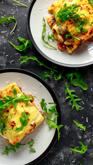 Homemade lasagna with minced beef bolognese and bechamel sauce topped wild arugula, parmesan cheese