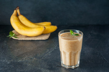 Glass of fruit banana - dates smoothie with mint leaves and ingridients on the dark background. Healthy, vegetarian, vegan diet food. Selective focus, space for text.