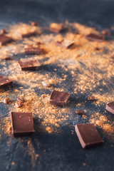 Chocolate bar pieces, cocoa powder and coffee beans on dark stone background. Background with chocolate. Slices of chocolate. Sweet food photo concept. Copyspace.