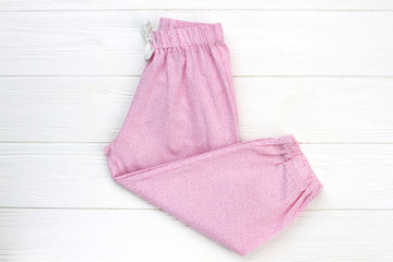 Pink pants on wooden background. Loose-fitting garment, easy to wear. Comfortable nightwear for girls.