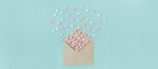 Fotobehang Multicolor sweets sugar candy hearts fly out of craft paper envelope on the light blue background . Valentine day. love concept. Gift, message for lover. Space for text. Wide banner. © okrasiuk