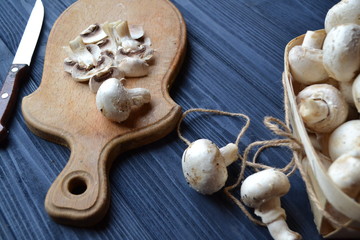 Mushrooms on the dark blue wooden desk. Cooking champignons.