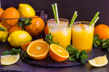 Naklejka na ściany i meble glass jar of fresh orange juice with fresh fruits on dark table.