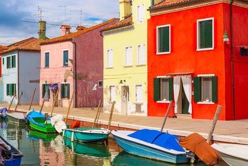 Fototapeta na wymiar Colorful houses and boats in Burano island with cloudy blue sky near Venice, Italy. Popular and famous tourist place