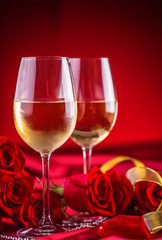 Valentines or wedding concept. Wine cups red roses and romantic setting for two in red. Greeting card for jubilee or aniversary