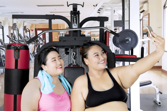 Obese women with smartphone in gym center