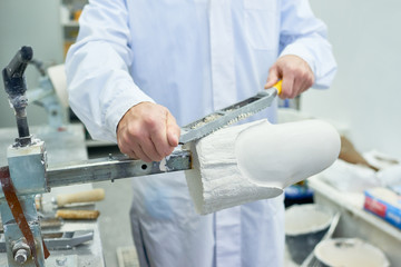 Front view mid-section  of unrecognizable prosthetist working in design laboratory shaping and...