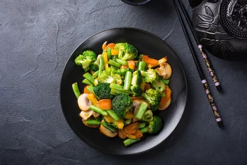 Photo sur Plexiglas Plats de repas Hot stir fried vegetables on black plate. Healthy asian food concept with copy space.