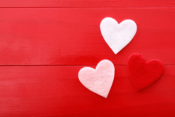 Felt hearts on a red wooden background