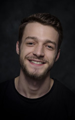 Portrait of a young man with a beard on a dark background.