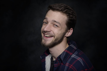 Fototapeta premium Portrait of a young man with a beard on a dark background.