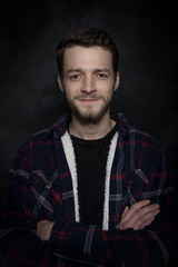 Portrait of a young man with a beard on a dark background.