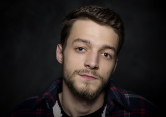 Portrait of a young man with a beard on a dark background.
