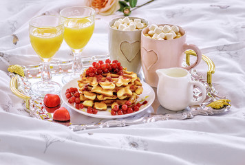 Romantic breakfast with Belgian waffles, honey, red currant, cappuccino with marshmallow and fresh orange juice