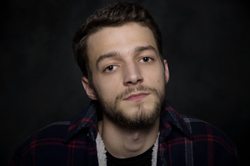 Portrait of a young man with a beard on a dark background.