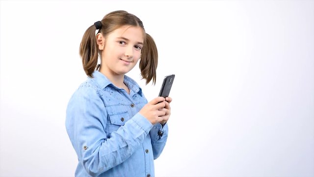 Toung pretty girl child using smartphone on gray background in studio