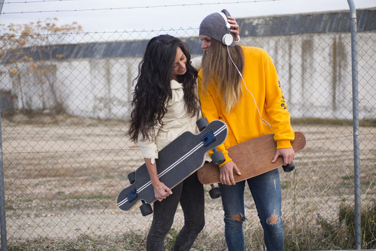 Two girls who play in the street with longboard
