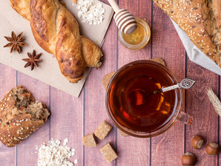 Grain bread with honey and nuts, a mug of tea brown sugar on dark wooden background