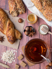 Grain bread with honey and nuts, a mug of tea brown sugar on dark wooden background