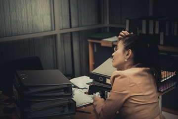 Asian woman working in office,young business woman stressed from work overload with a lot file on the desk