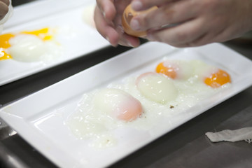 Chef put soft-boiled eggs on white plate in the restaurant kitchen. blurry background.