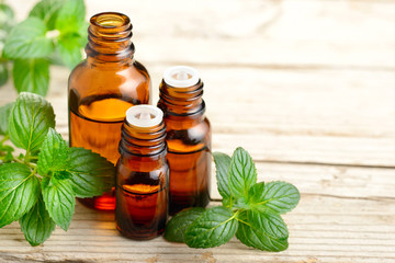 Peppermint essential oil and leaves on the wooden board