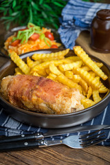 Fried chicken breast stuffed with mushrooms and cheese wrapped in ham served with fries and salad.