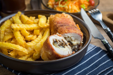 Fried chicken breast stuffed with mushrooms and cheese wrapped in ham served with fries and salad.
