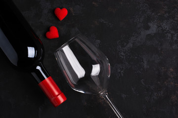 Bottle and glass of wine With 2 red hearts On the old black rusty floor.