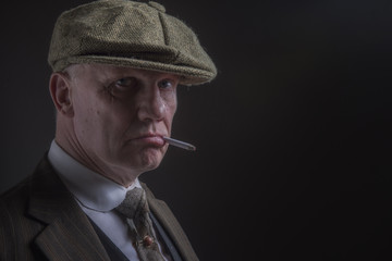 Portrait of a mature man in Victorian gangster outfit smoking a cigarette with copy space