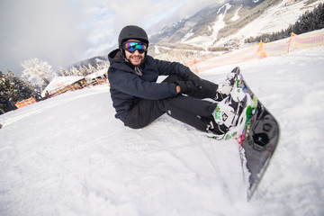 Fototapeta na wymiar Snowboarder sitting on a ski slope before ride