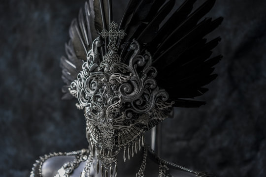 Steampunk, handmade piece, silver jewelry costume with chains and coins. wears a headdress made with feathers and gothic pieces