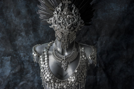 Steampunk, handmade piece, silver jewelry costume with chains and coins. wears a headdress made with feathers and gothic pieces