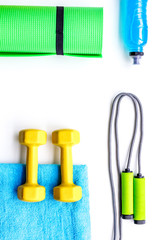 Do fintess in gym. Dumbbells, jump rope, mat, water on white background top view copy space