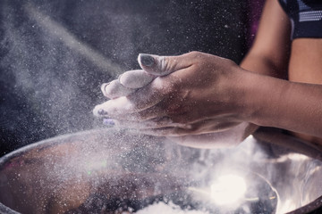 Fototapeta na wymiar Female fitness model clapping hands with talc powder in a gym just before doing exercise. Close-up