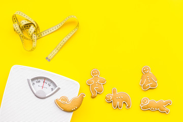 Ways for lose weight. Sport. Cookies in shape of yoga asans near scale and measuring tape on bright...