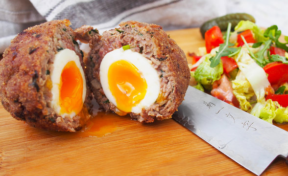 Traditional scotch eggs on a wooden plate. Scotch eggs and salad