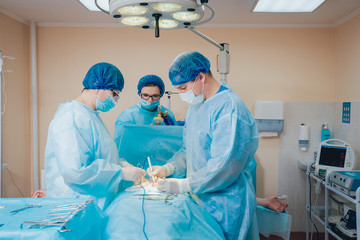Group of surgeons in operating room with surgery equipment.