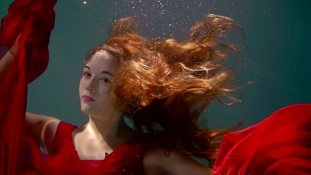portrait of a pretty woman who swims in the pool, she is dressed in a red dress