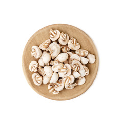 Cut mini champignons on a round wooden cutting board. Isolated over white background..