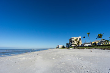 USA, Florida, Endless coast of barefoot beach with some houses and palm trees in the morning