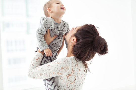 Mother and son playing in a white room. Cute child boy with his mom in white clothes. Happy and lovely Family, communicate with kid