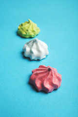 Red, white and green meringue cakes on a blue background.