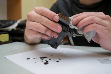 The repair specialist keeps a broken printhead from the inkjet printer in the hands stained. Repair...