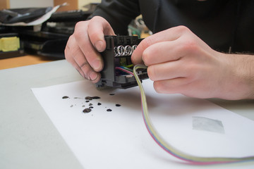 The repair specialist keeps a broken printhead from the inkjet printer in the hands stained. Repair...