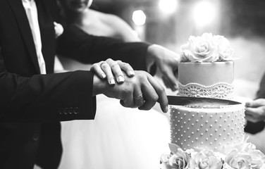 A bride and a groom is cutting their wedding cake. beautiful cake. nicel light. wedding concept. black and white photo 