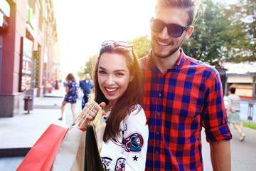 Naklejka premium Young happy couple with shopping bags in the city